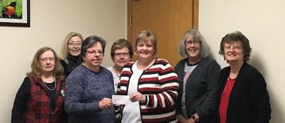 Terry Wood presenting the check to Jo Roling, LPEC committee, with Thrift Shop representatives standing behind