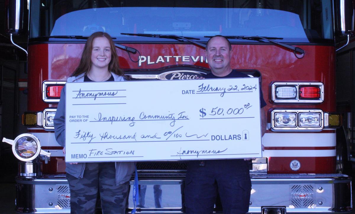 Chief Ryan Simmons and fire fighter Brianne Beissmann accepting donation check to Platteville Fire Facility Project